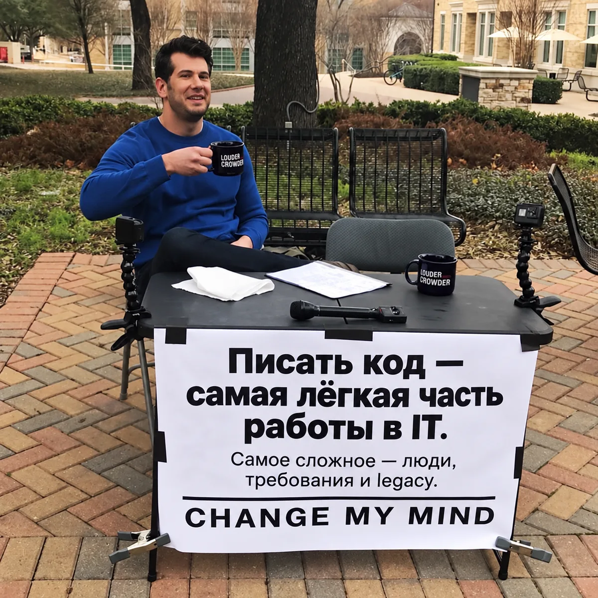 Мем Change My Mind: человек сидит с кофе за раскладным столиком на улице, на баннере надпись «Писать код — самая лёгкая часть работы в IT. Самое сложное — люди, требования и legacy. Change my mind»